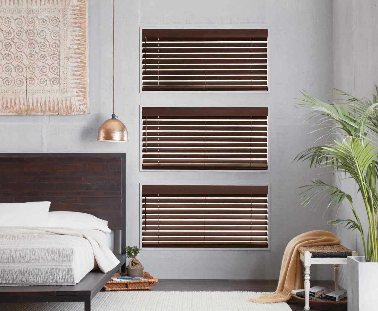 Three windows in a bedroom covered by dark wood blinds near Youngstown, OH